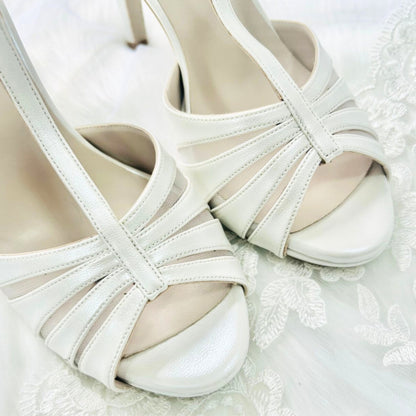 A pair of elegant ivory wedding shoes resting on a delicate lace background, showcasing their intricate design.